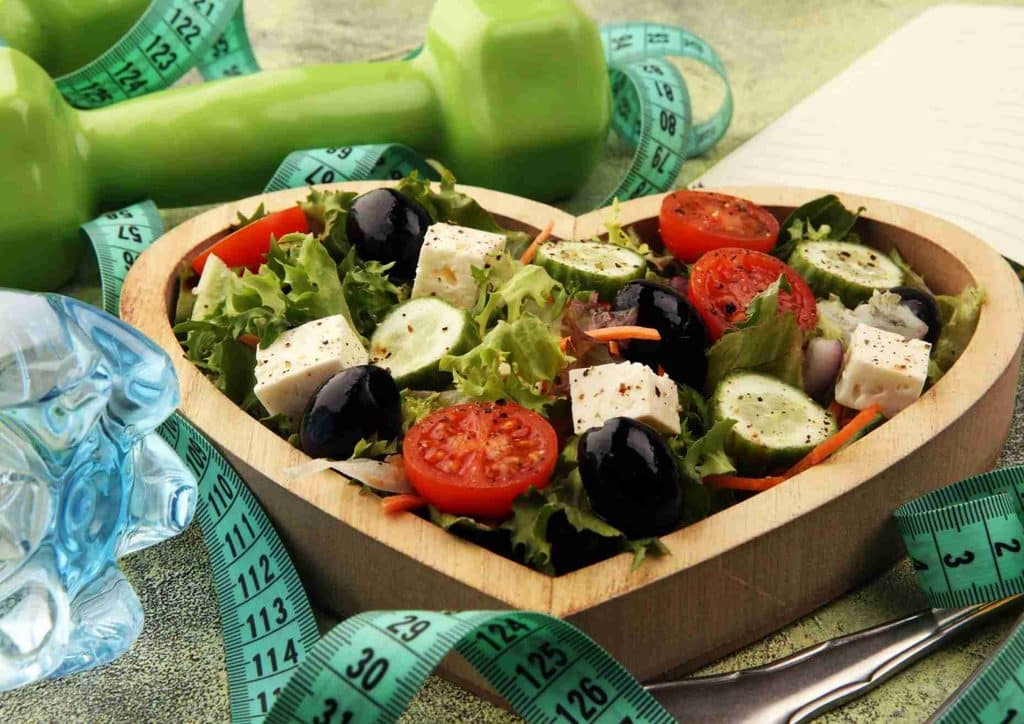 Easy Meals for Weight Loss When You're Short on Time 18 A fresh salad accompanied by a measuring tape and a green water bottle, symbolising healthy eating and fitness.