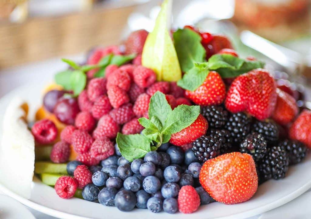 High Fibre Diet for Weight Loss: Why Fibre Keeps You Full 12 A vibrant assortment of fresh fruit on a plate, prominently displaying various berries.