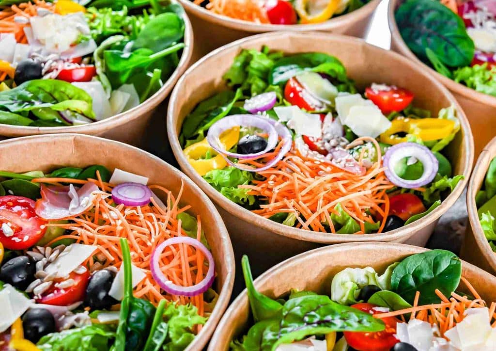 Easy Meals for Weight Loss When You're Short on Time 16 Close-up of multiple bowls filled with colourful salads, showcasing a variety of fresh vegetables and toppings.