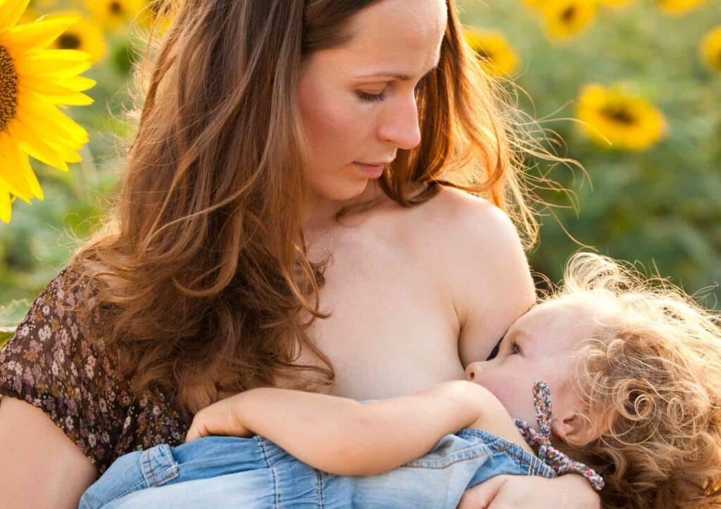 Losing Weight While Breastfeeding: What's Safe and Realistic 35 A mother breastfeeding her baby outdoors, surrounded by greenery, highlighting the connection between nature and nurturing.