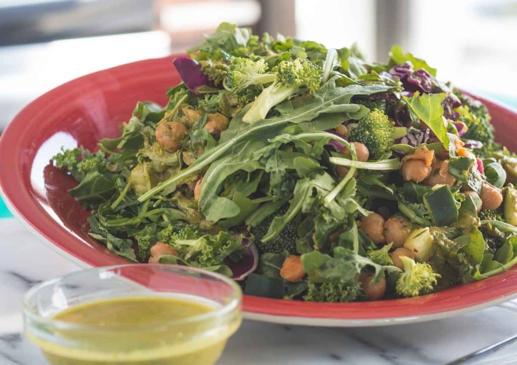 Vegetarian Diet for Weight Loss: How to Get It Right 45 A vibrant salad featuring greens, chickpeas, and dressing, presented on a wooden table.