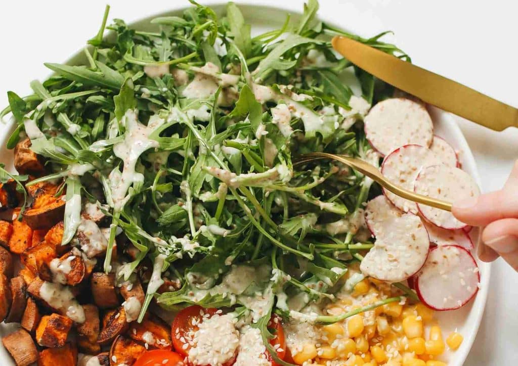 Vegetarian Diet for Weight Loss: How to Get It Right 57 A person slices a fresh salad with a knife, showcasing vibrant vegetables and greens on a cutting board.