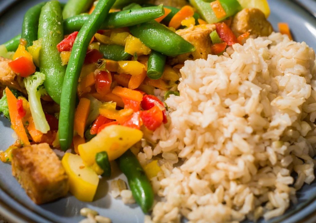 Healthy Dinners for Weight Loss: Easy Weeknight Ideas 11 A dish containing fluffy rice, assorted vegetables, and golden-brown tofu, presented on a white plate.