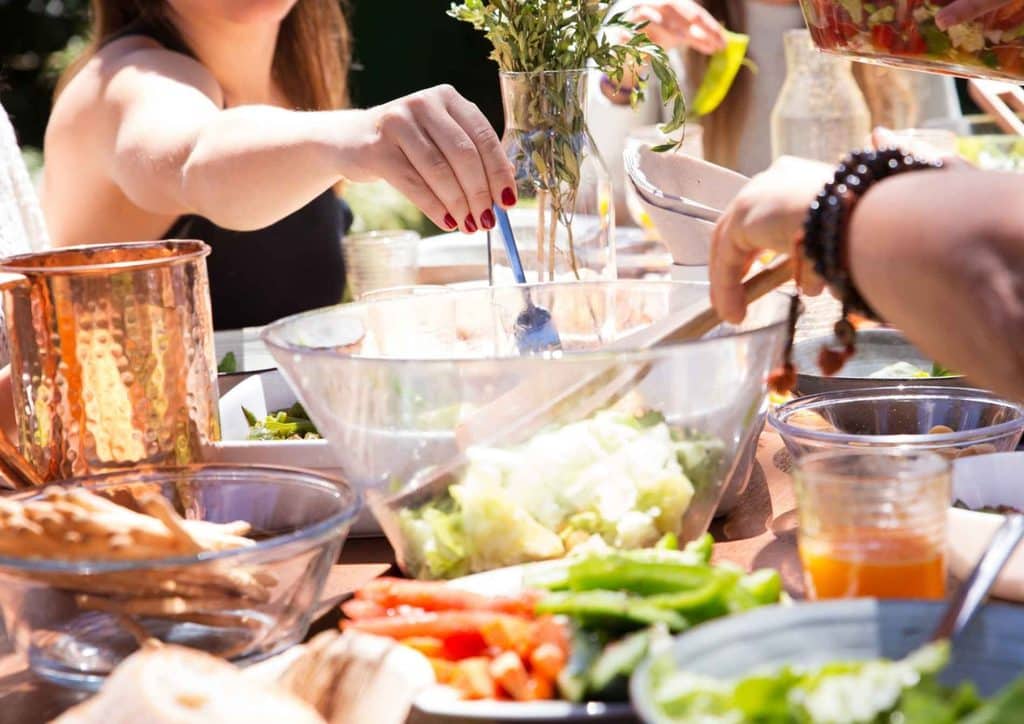 Healthy Lunches for Weight Loss: Work and Home Ideas 10 A diverse group of people enjoying a meal together at a picnic table in a sunny outdoor setting.