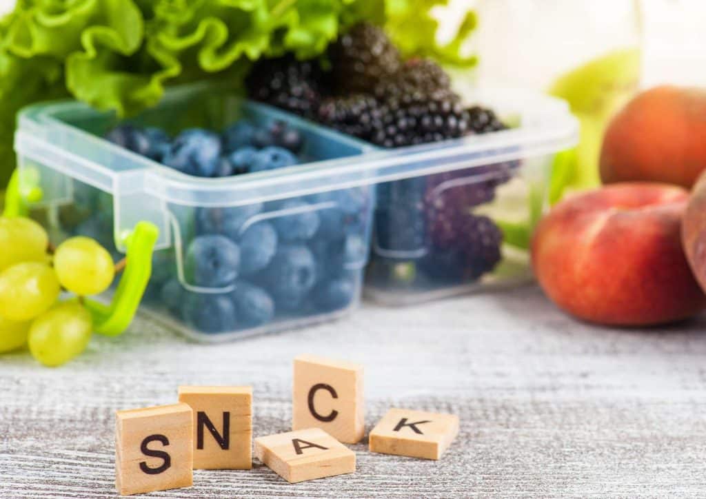 Healthy Snacks for Weight Loss That Actually Keep You Full 20 A wooden table displays an assortment of snack foods, including fresh fruits and vegetables arranged attractively.