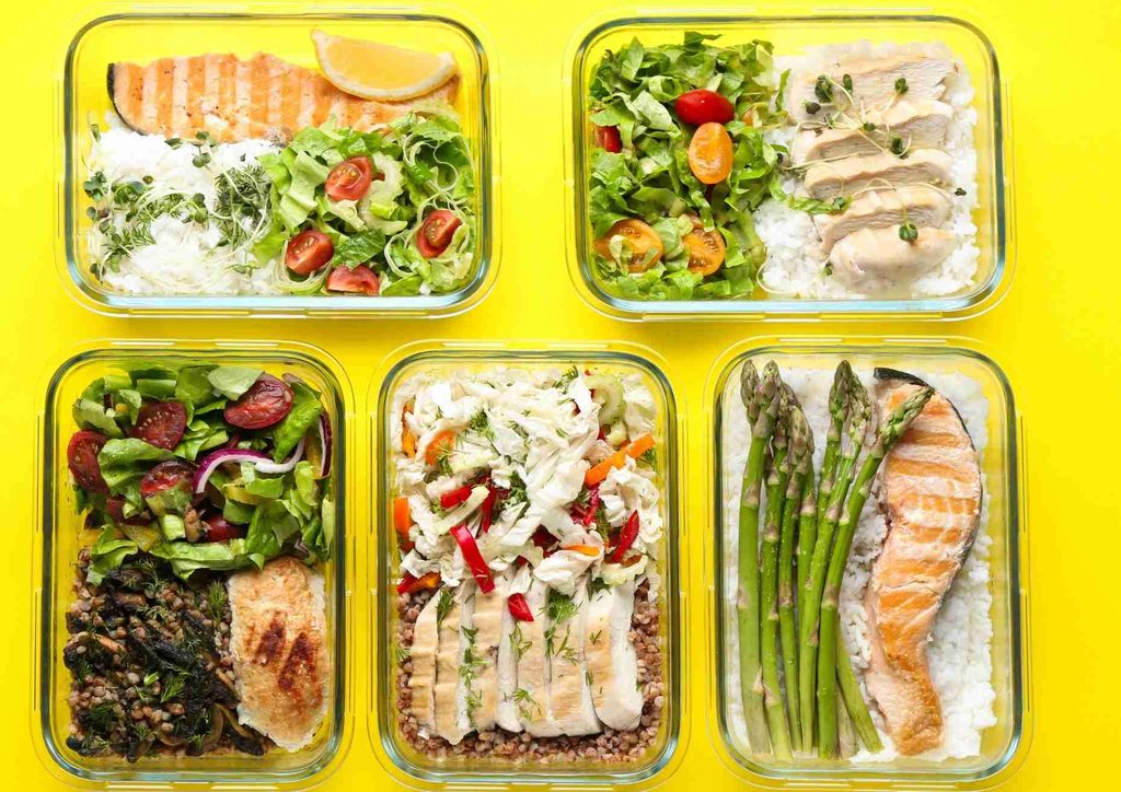 Healthy Lunches for Weight Loss: Work and Home Ideas 9 Six food containers featuring asparagus, chicken, rice, and assorted vegetables arranged neatly for meal prep.