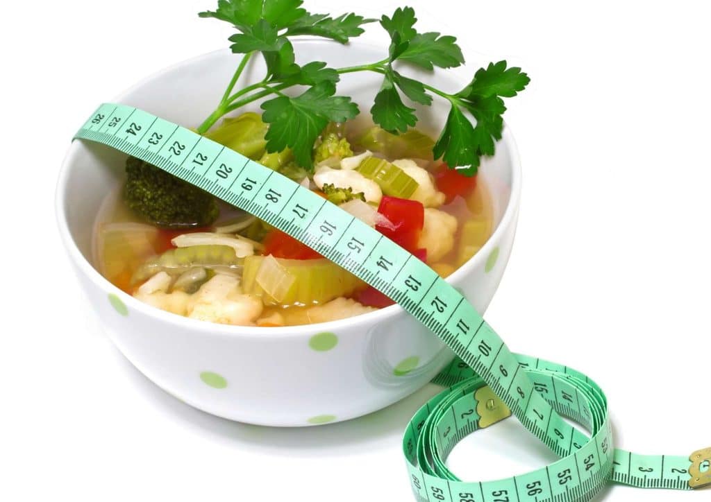 Easy Meals for Weight Loss When You're Short on Time 1 A bowl of fresh vegetables surrounded by a measuring tape, illustrating the concept of healthy eating and mindful portion sizes.