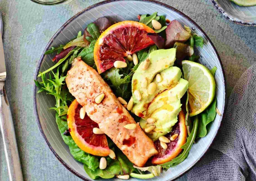 Easy Meals for Weight Loss When You're Short on Time 7 A plate featuring grilled salmon, sliced avocado, and vibrant blood orange segments arranged artfully.