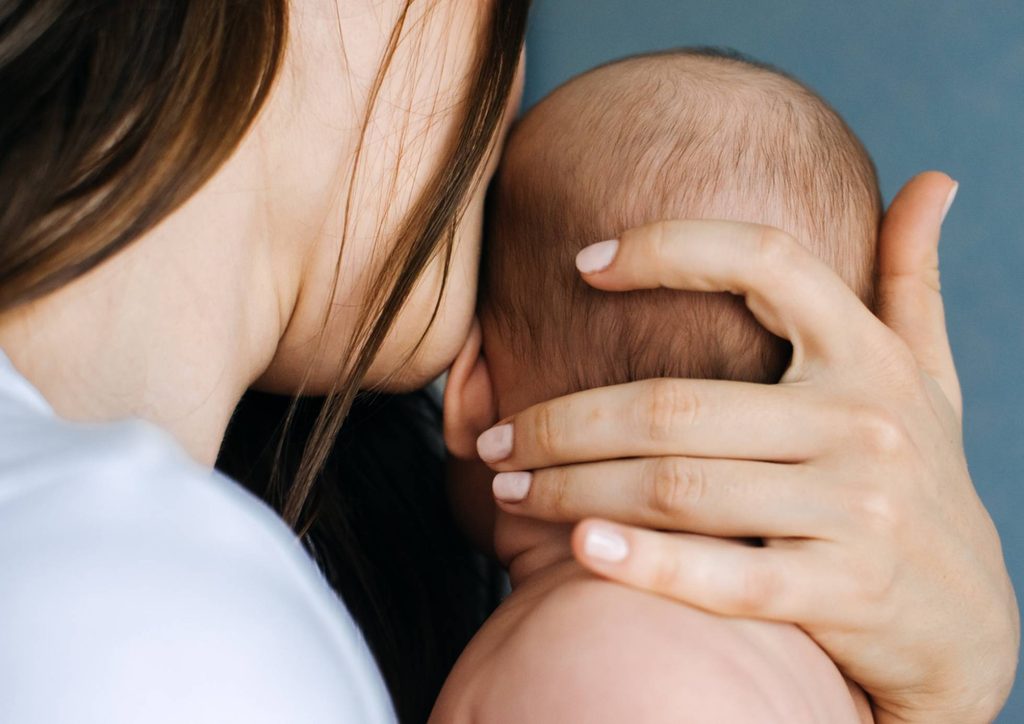 Postpartum Weight Loss: A Gentle, Realistic Guide 12 A woman gently holds a baby close to her face, showcasing a tender moment of affection and connection.