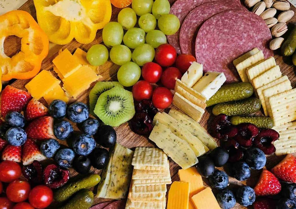 Healthy Snacks for Weight Loss That Actually Keep You Full 28 A cutting board displaying a vibrant selection of fresh fruits and vegetables, showcasing their natural colours.