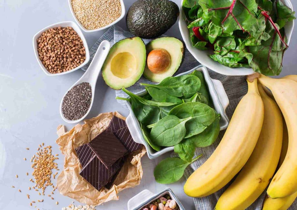 What Is a Balanced Diet for Weight Loss? 6 A variety of healthy foods including bananas, spinach, avocado, nuts, and seeds arranged on a wooden surface.