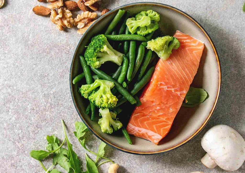 What Is a Balanced Diet for Weight Loss? 23 A plate featuring grilled salmon, steamed broccoli, and sautéed green beans arranged neatly.