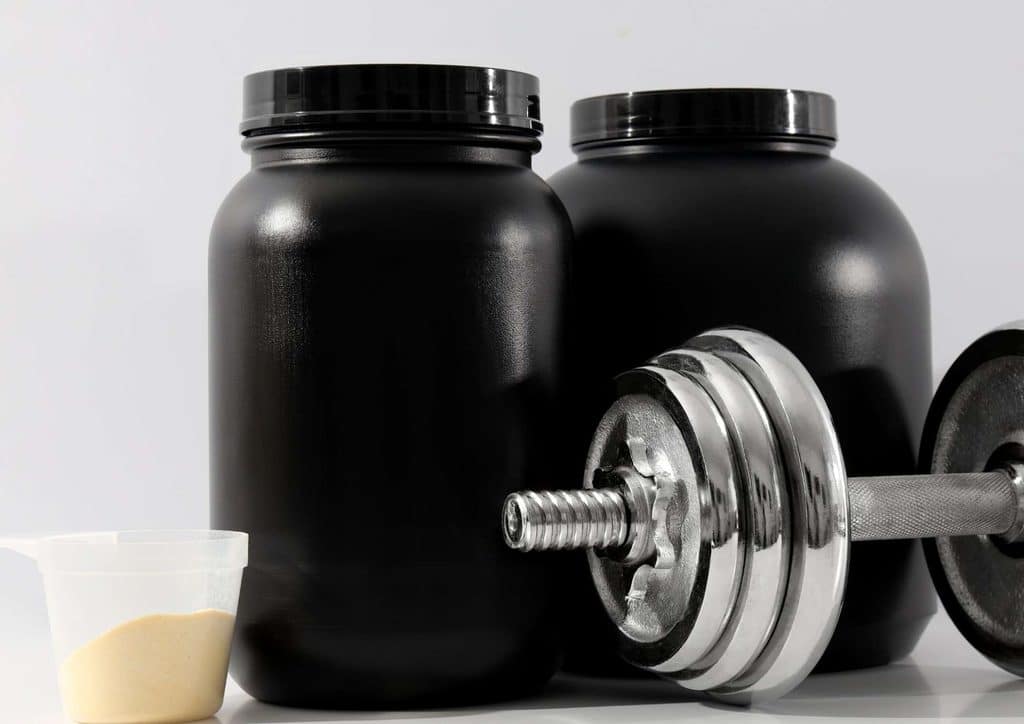 Is Whey Protein Good for Weight Loss? 18 Two black bottles containing white powder beside a black dumbbell on a flat surface.