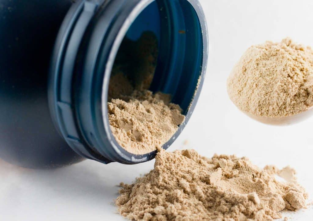 Is Whey Protein Good for Weight Loss? 19 A scoop of protein powder is being poured into a clear container, showcasing the powder's texture and colour.