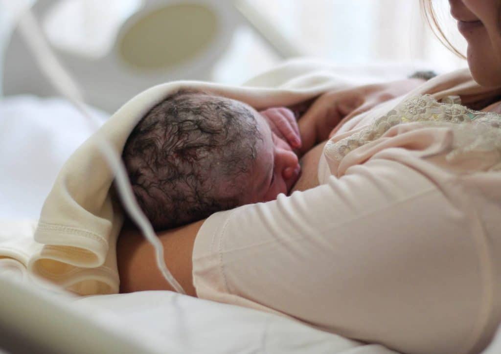 Losing Weight While Breastfeeding: What's Safe and Realistic 72 A woman cradles her newborn in a hospital bed, showcasing a tender moment of maternal bonding.