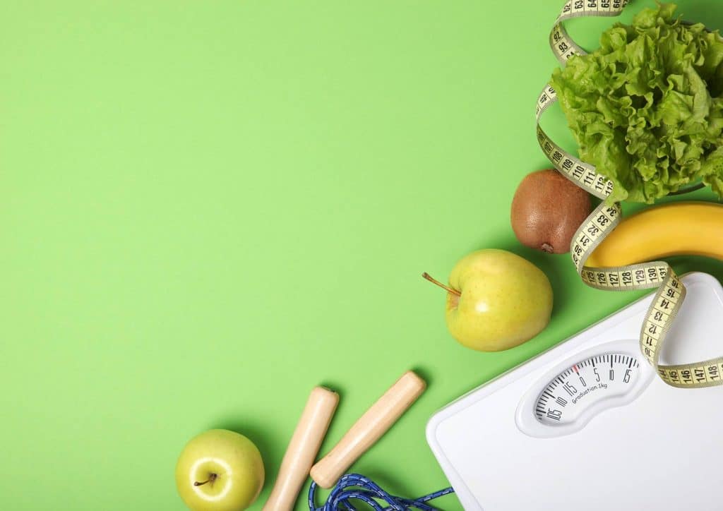 What Is a Balanced Diet for Weight Loss? 17 Fresh fruits and vegetables displayed on a green backdrop, representing the essence of a healthy diet.