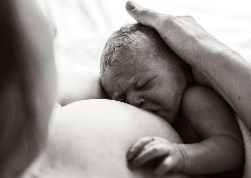 Losing Weight While Breastfeeding: What's Safe and Realistic 71 A woman gently breastfeeding her baby, showcasing a nurturing moment between mother and child.