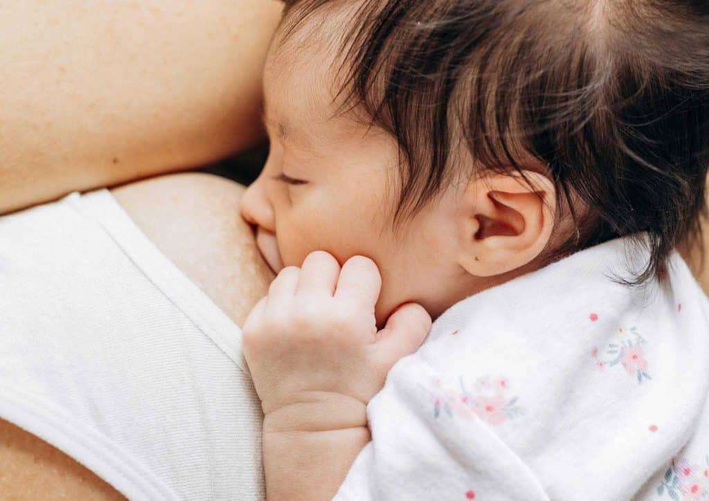 Losing Weight While Breastfeeding: What's Safe and Realistic 76 A woman cradles her baby close to her chest, showcasing a tender moment of bonding and nurturing.