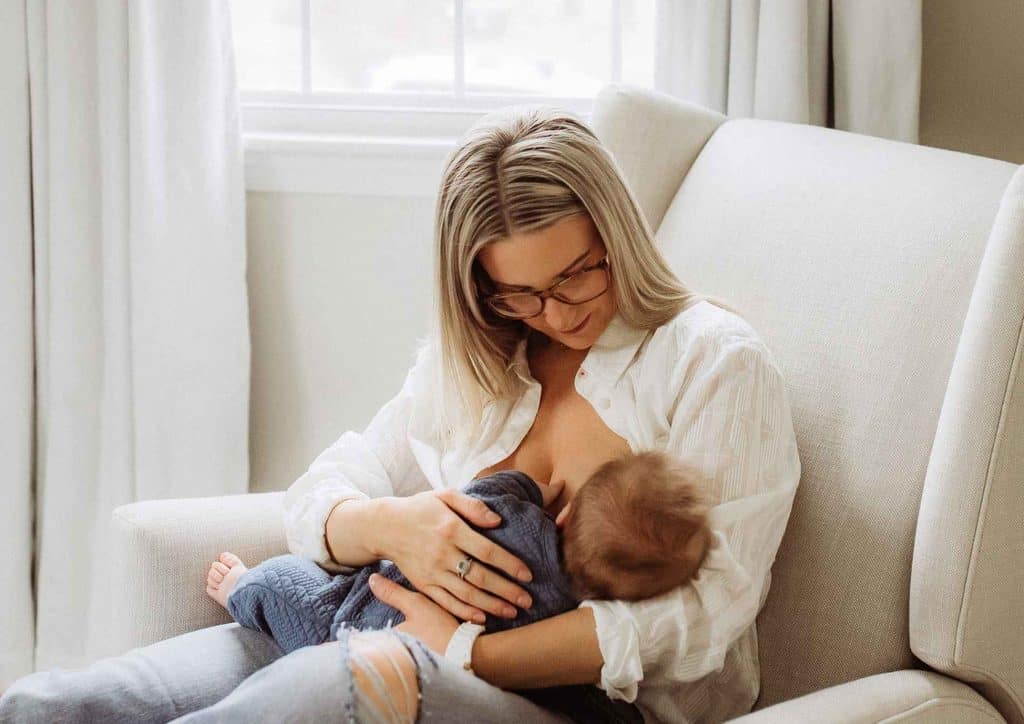 Losing Weight While Breastfeeding: What's Safe and Realistic 1 A woman sits in a chair, breastfeeding her baby, creating a nurturing and intimate moment between them.