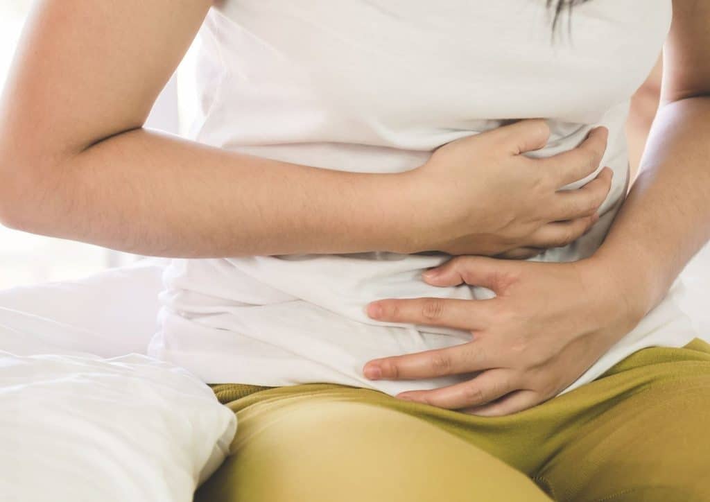 High Fibre Diet for Weight Loss: Why Fibre Keeps You Full 13 A woman lying on her bed, holding her stomach in discomfort, indicating abdominal pain.