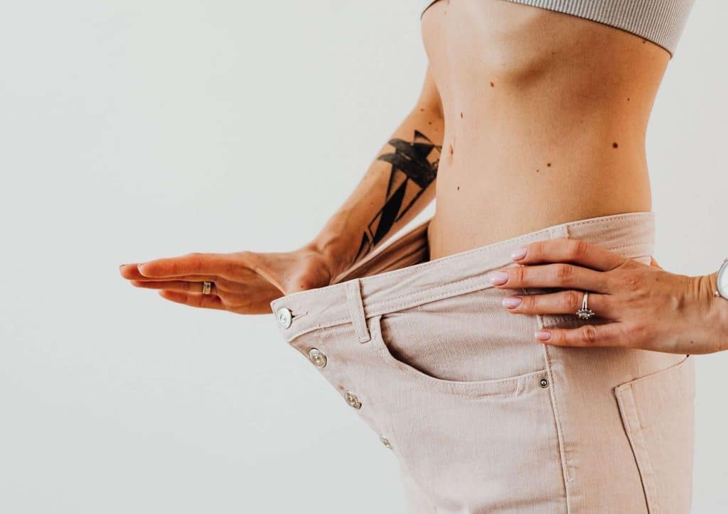High Fibre Diet for Weight Loss: Why Fibre Keeps You Full 2 A woman with stomach tattoos holds her pants, showcasing her body art and casual attire.