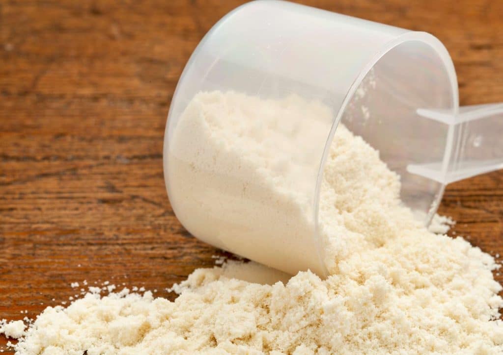 Is Whey Protein Good for Weight Loss? 4 A scoop of white powder rests on a wooden table surface, indicating a potential ingredient or substance.