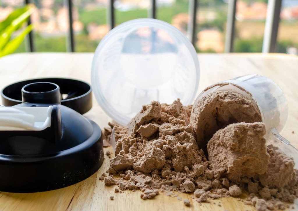 Is Whey Protein Good for Weight Loss? 3 A blender next to a container of protein powder, ready for mixing a protein shake.
